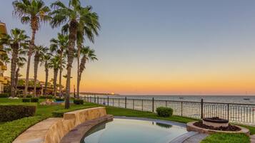 A pool with a view of the ocean and palm trees.