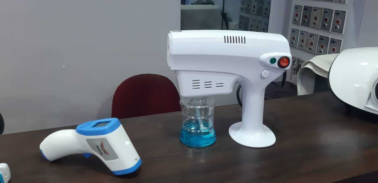 A white hair dryer on a wooden table with a blue container and a blue and white device.