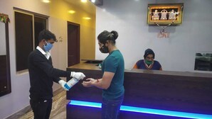 A reception area with a marble floor, a reception desk with a blue LED light strip, and a framed picture on the wall. - Hotel Tara Tower (Koderma)