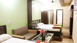 A hotel room with two beds, a sofa, a small table with a vase, and a ceiling fan. - Hotel Tara Tower (Koderma)