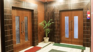 A hallway with wooden doors, a potted plant, and a fire extinguisher. - Hotel Tara Tower (Koderma)