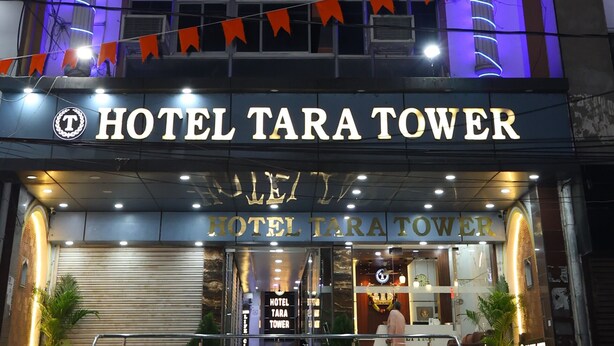 A hotel named 'Hotel Tara Tower' with a prominent sign, a balcony, and a series of lights along the facade.