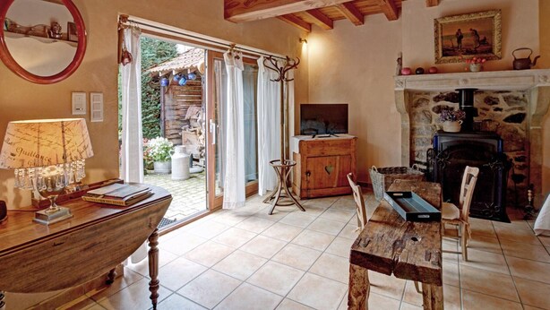 Une pièce chaleureuse avec un plafond en bois, une cheminée, une table à manger et un téléviseur.