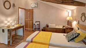 Une chambre confortable avec un plafond en pente, un bureau en bois, un lit recouvert d’une couverture jaune et une table de chevet avec une lampe.