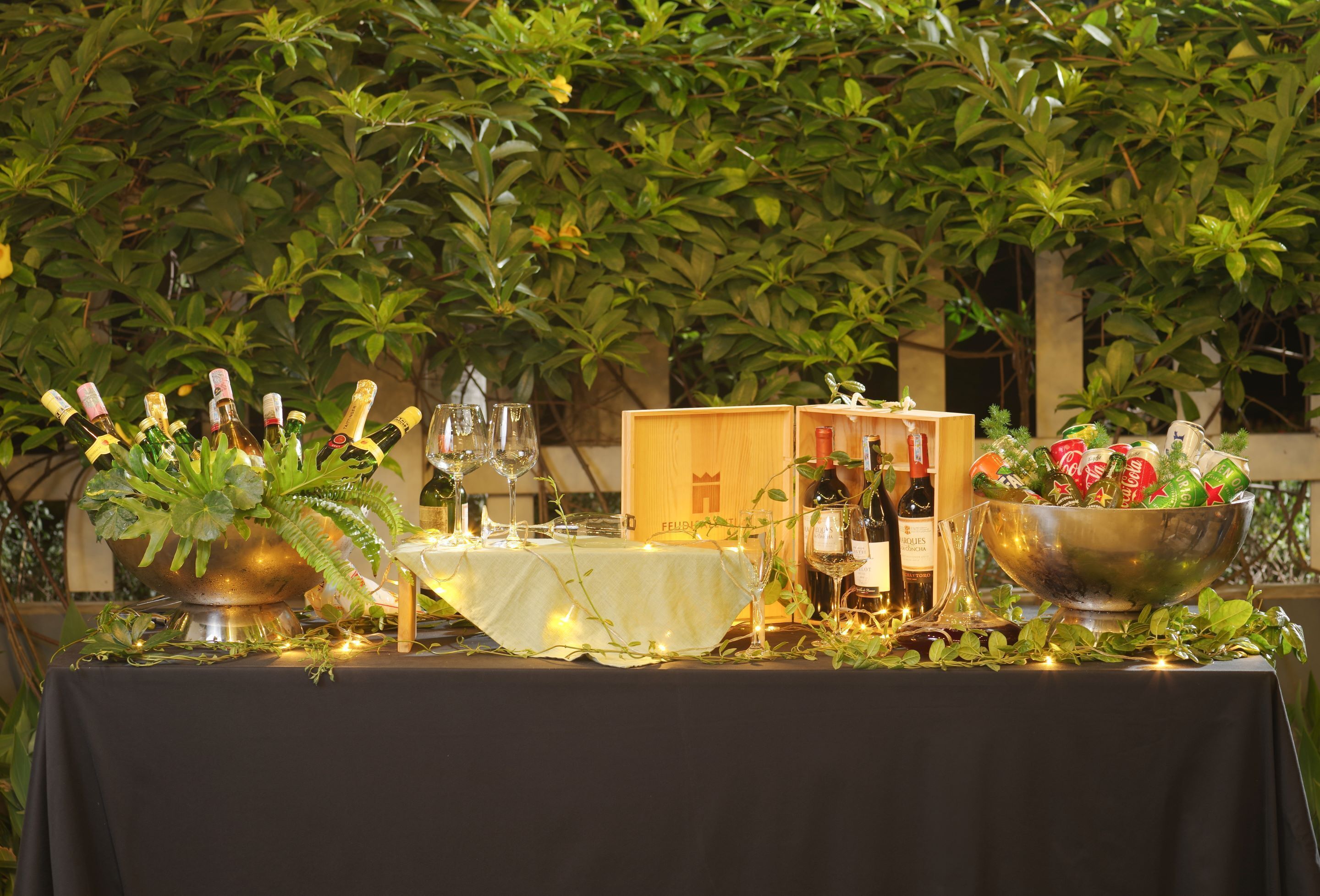 A table set for a meal with wine bottles, glasses, and a bowl of fruit.