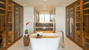 A modern bathroom with a freestanding bathtub, wooden cabinets, and a marble floor. - Oakwood Ha Long (Bai Chay)