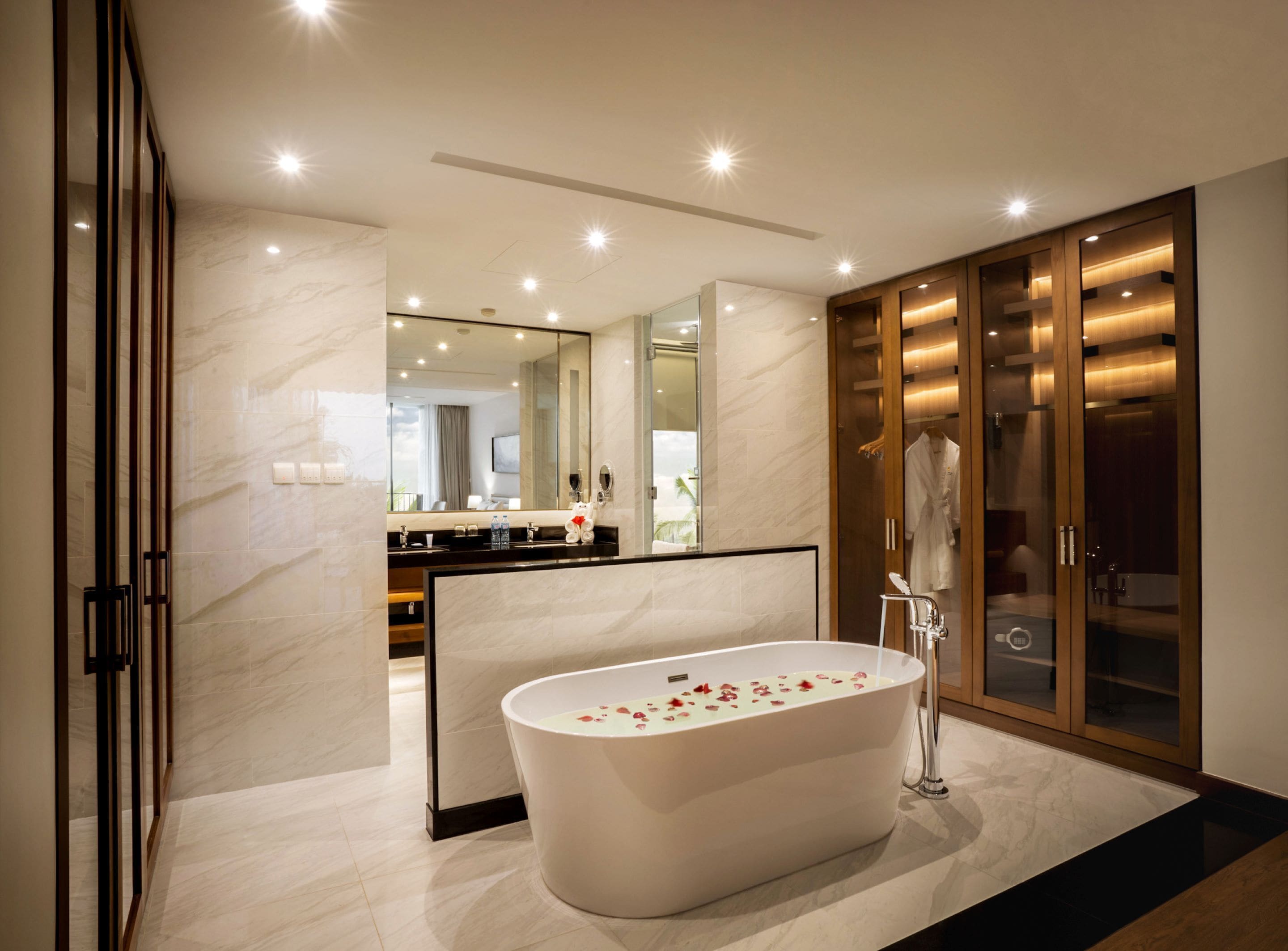 A modern bathroom with a freestanding bathtub, a large mirror, and a walk-in closet with sliding doors.