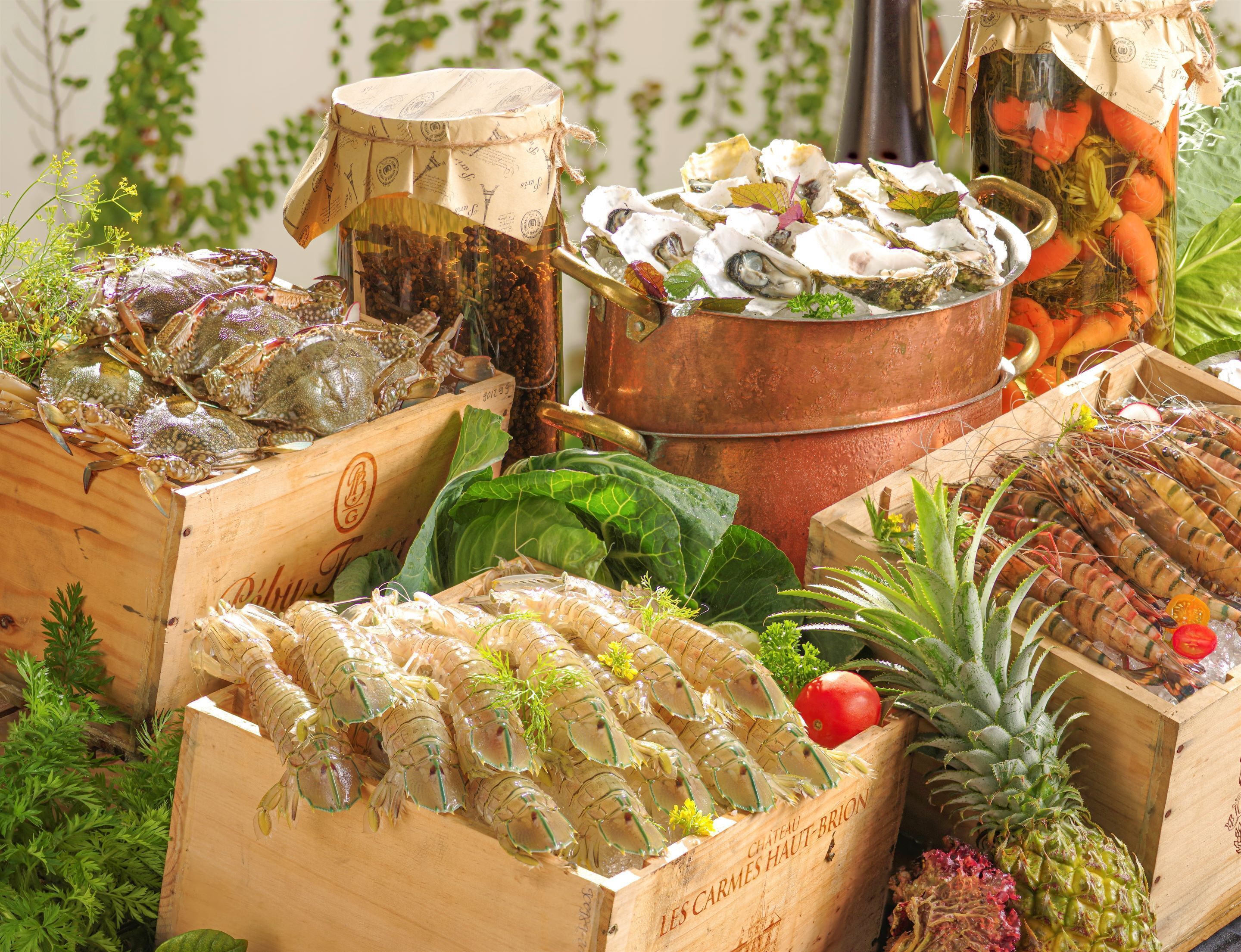 A variety of seafood including lobsters, oysters, and crayfish, displayed in wooden crates and a copper pot.