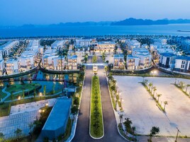 A modern hotel complex with a central courtyard, multiple buildings, and a view of the sea.