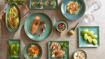 A variety of dishes on teal plates, including a rolled meat dish, a bowl of soup, and a salad with vegetables and nuts.