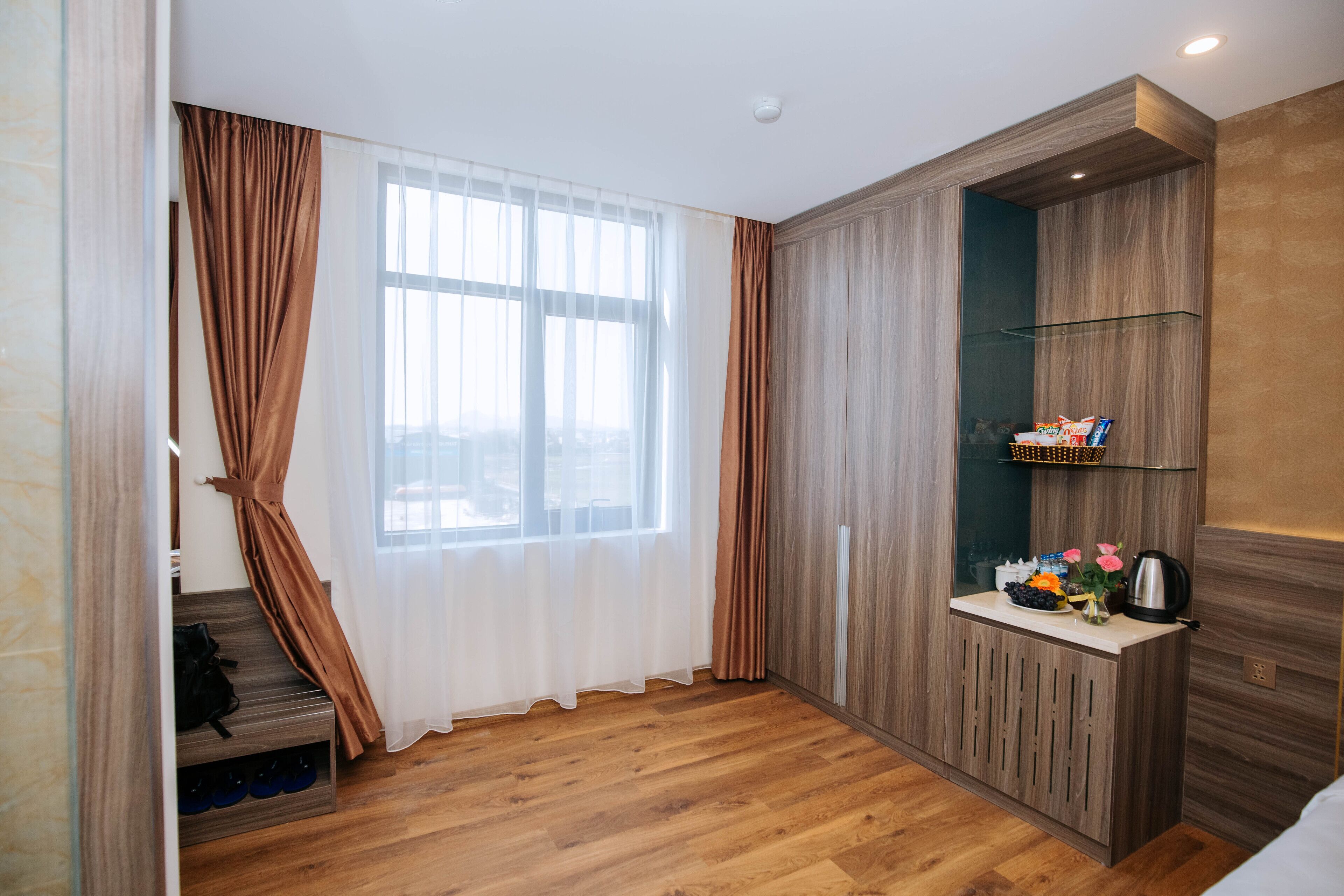 Une chambre moderne dotée d’une grande fenêtre, d’un plancher en bois, d’une étagère intégrée pour les articles de toilette et d’un escalier avec un meuble à chaussures.