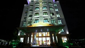Hotel de varios pisos con una entrada destacada y un árbol de Navidad al frente.