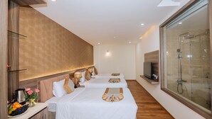 Habitación de hotel con dos camas, televisión, ducha y suelo de madera.