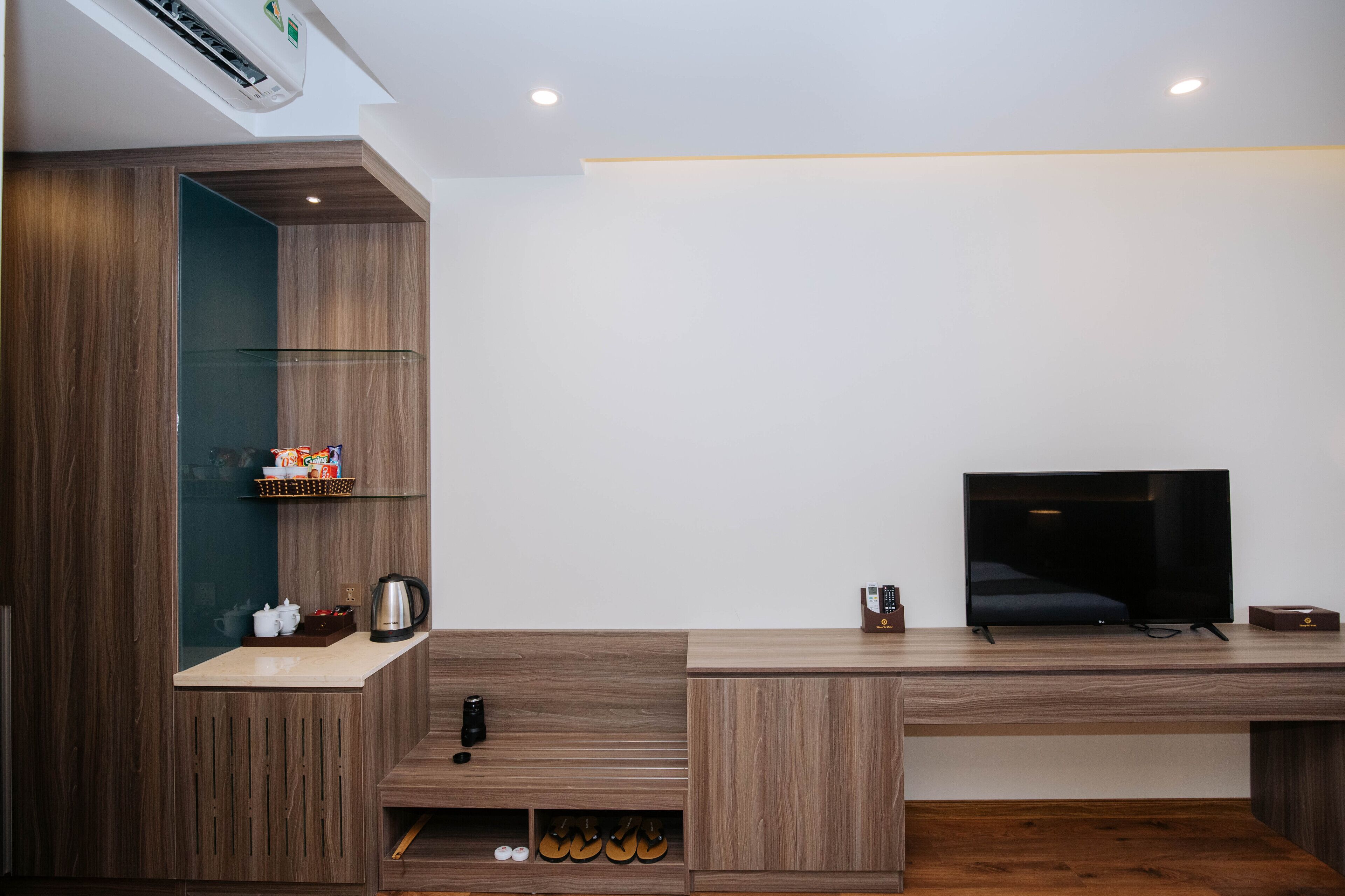 Una sala de estar moderna con mueble bajo para entretenimiento de madera, un televisor de pantalla plana y una cafetera empotrada.