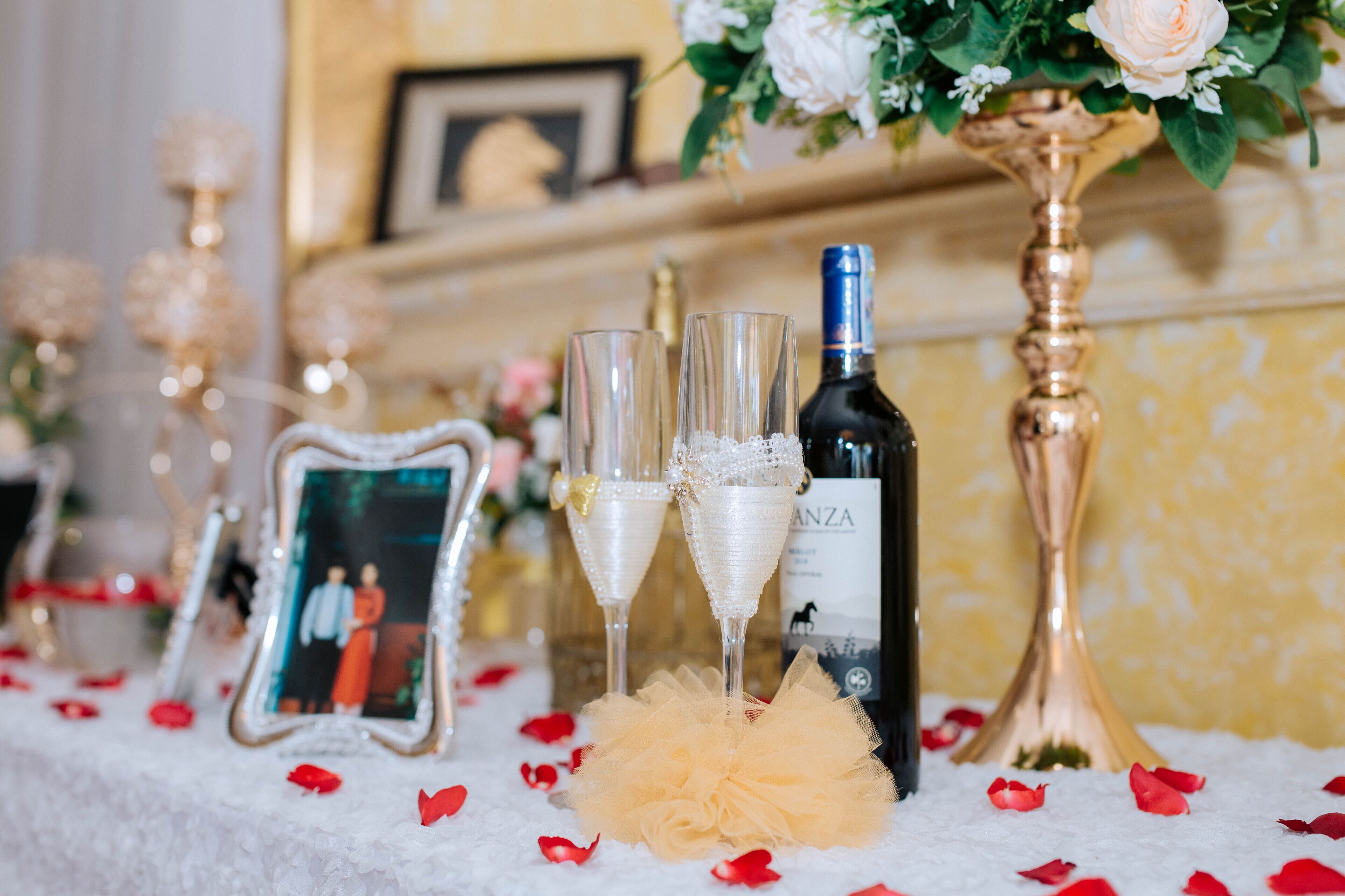 A table with champagne glasses, a bottle of wine, a framed photo, and a decorative vase.