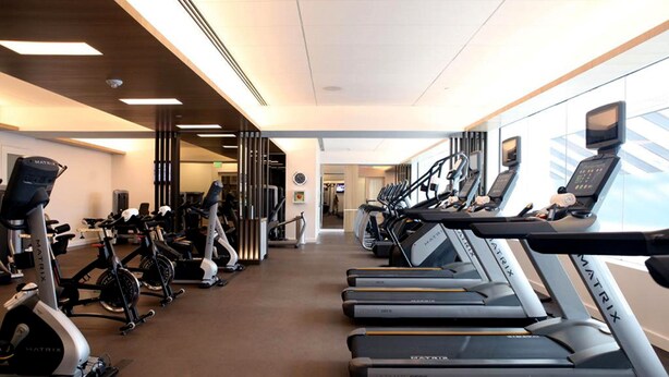 Un gimnasio con cintas de correr, bicicletas estáticas y máquinas elípticas.