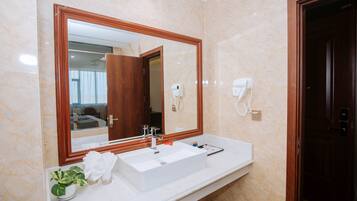Un bagno con uno specchio grande, un lavandino bianco e un asciugacapelli montato a parete.