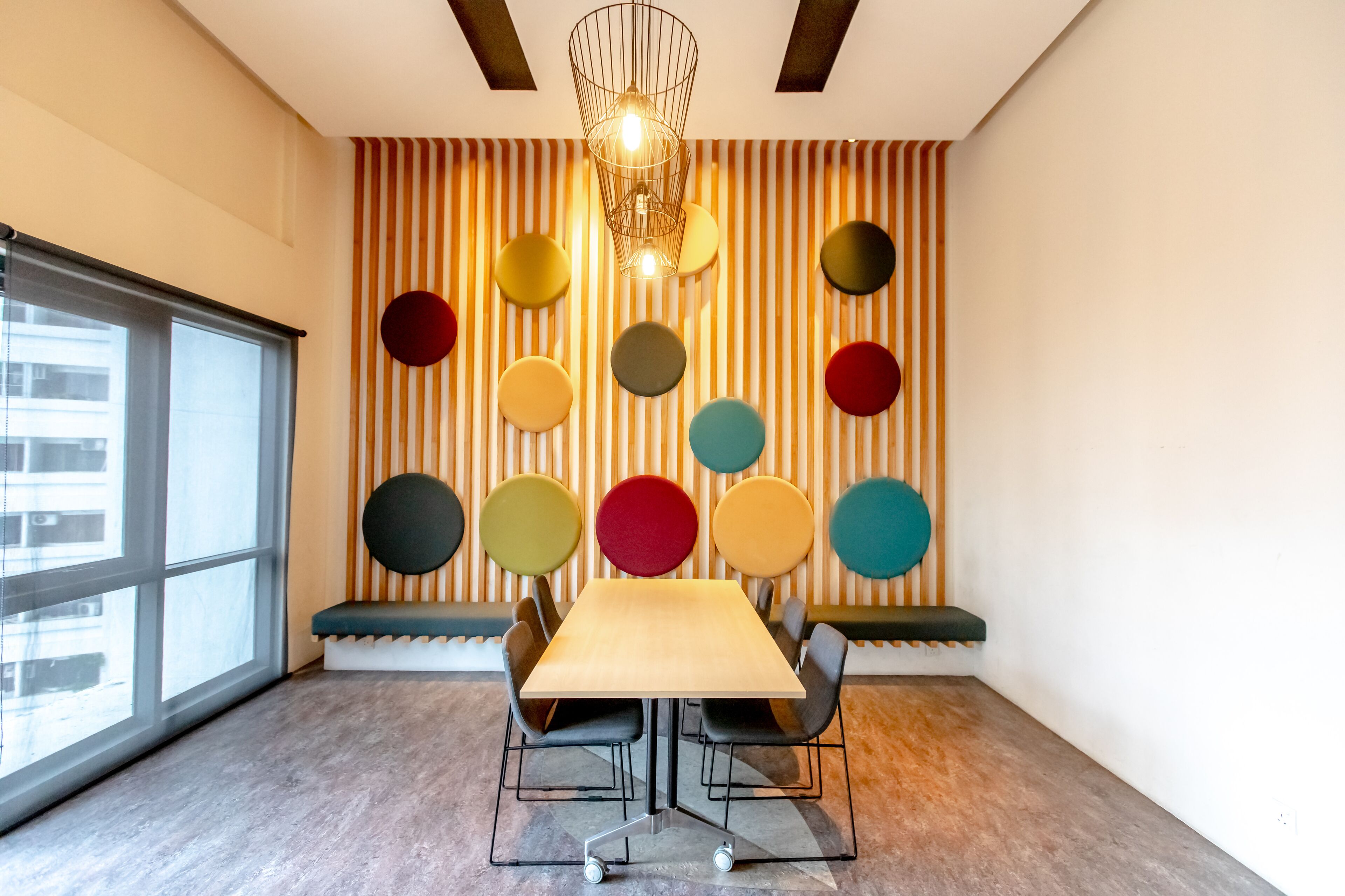 A modern meeting room with a large table, black chairs, and colorful circular wall decorations.