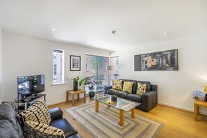 A modern living room with a sofa, coffee table, TV, and artwork.
