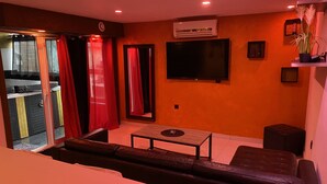 Una sala de estar con sofá, una mesa de centro y un televisor montado en la pared.