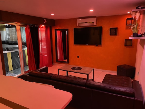 A living room with a sofa, a coffee table, and a TV mounted on the wall.