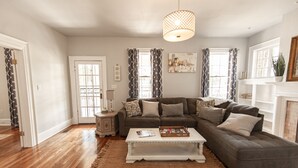 Un salon avec un canapé d’angle, une table basse blanche et un tapis à motifs.