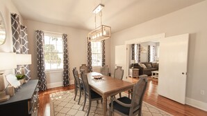 Un coin repas avec une table en bois, six chaises et un lustre.