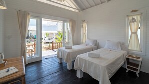Una habitación con dos camas individuales, una mesa de madera y vistas al exterior.