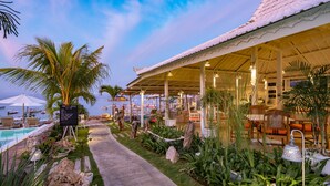 Un resort con piscina, mobiliario exterior y una zona cubierta con plantas.