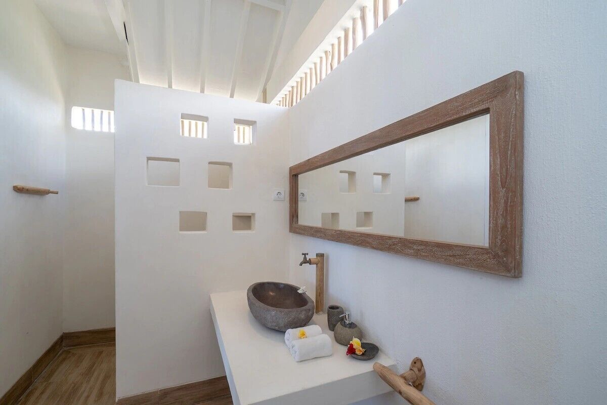 Un baño con un lavabo de piedra, una puerta de madera y un espejo en la pared.