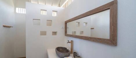 Un baño con un lavabo de piedra, una puerta de madera y un espejo en la pared.