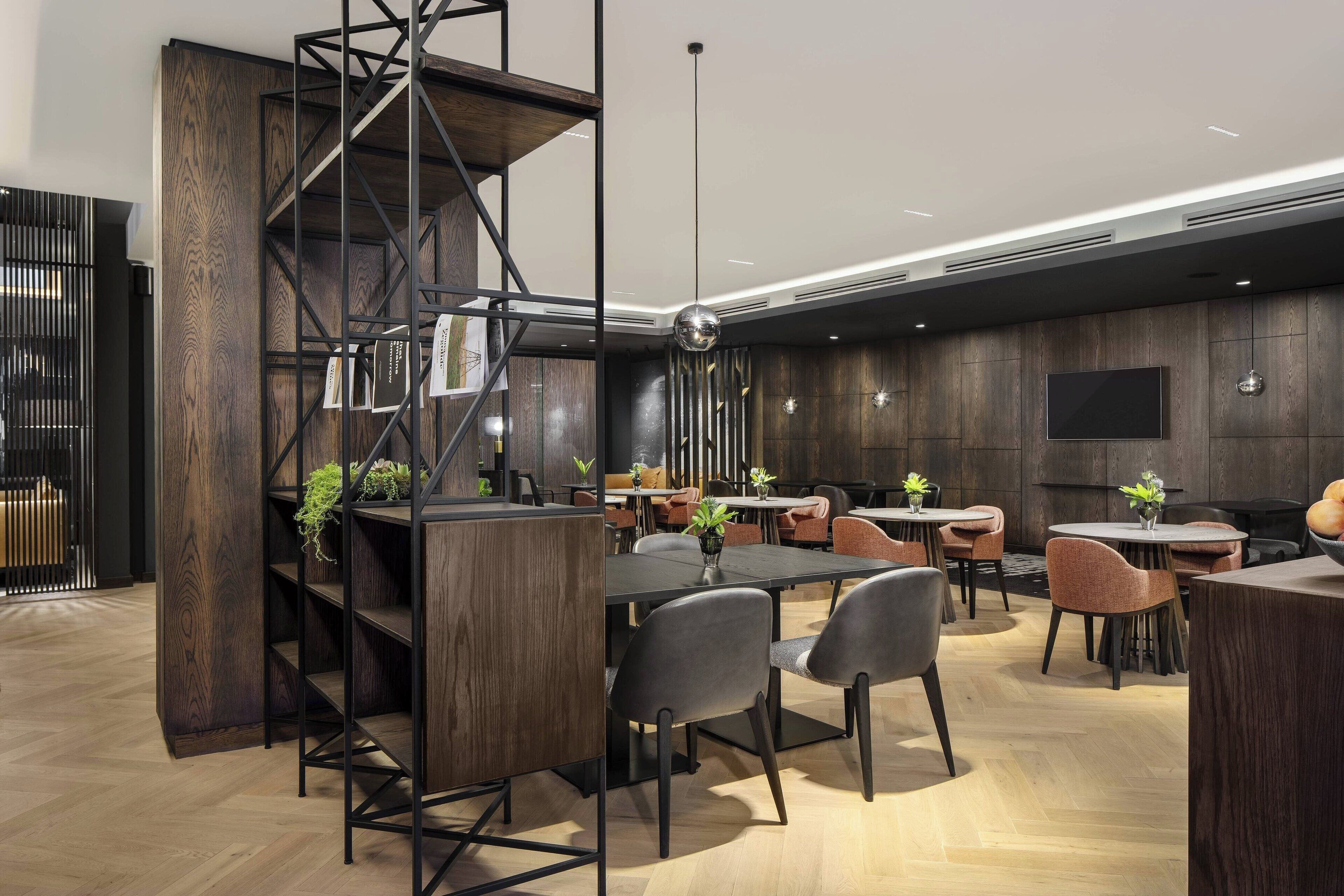 Un restaurante moderno con interior de madera, estanterías de metal negro y varias mesas y sillas.