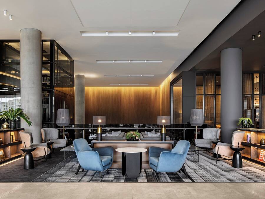 A modern lobby with a central seating area, large columns, and a wooden wall.