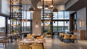 A modern restaurant with high ceilings, large windows, and a variety of seating arrangements. - Johannesburg Marriott Hotel Melrose Arch (Johannesburg)
