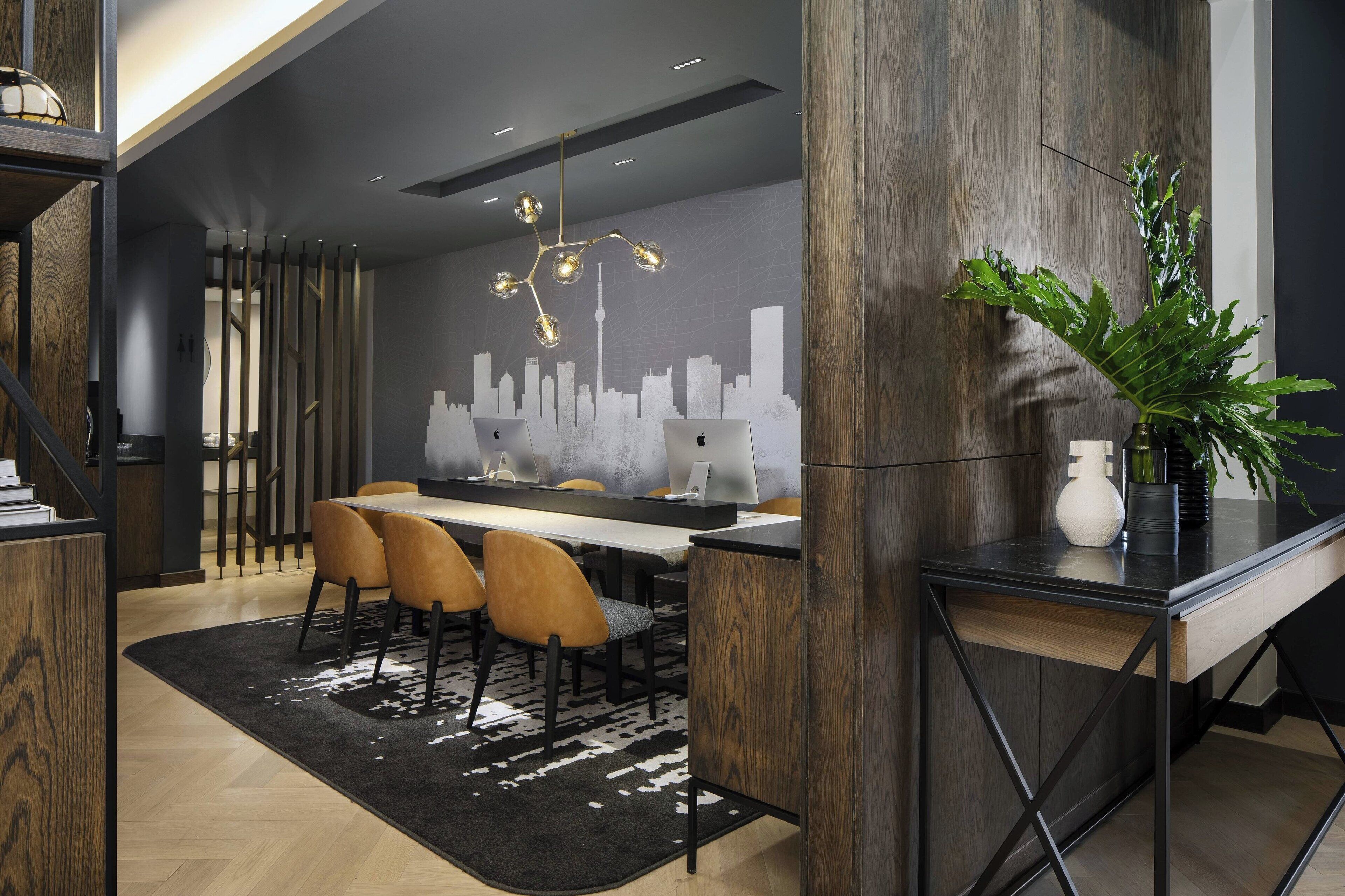 A modern dining area with a cityscape mural, wooden accents, and a black and white rug.