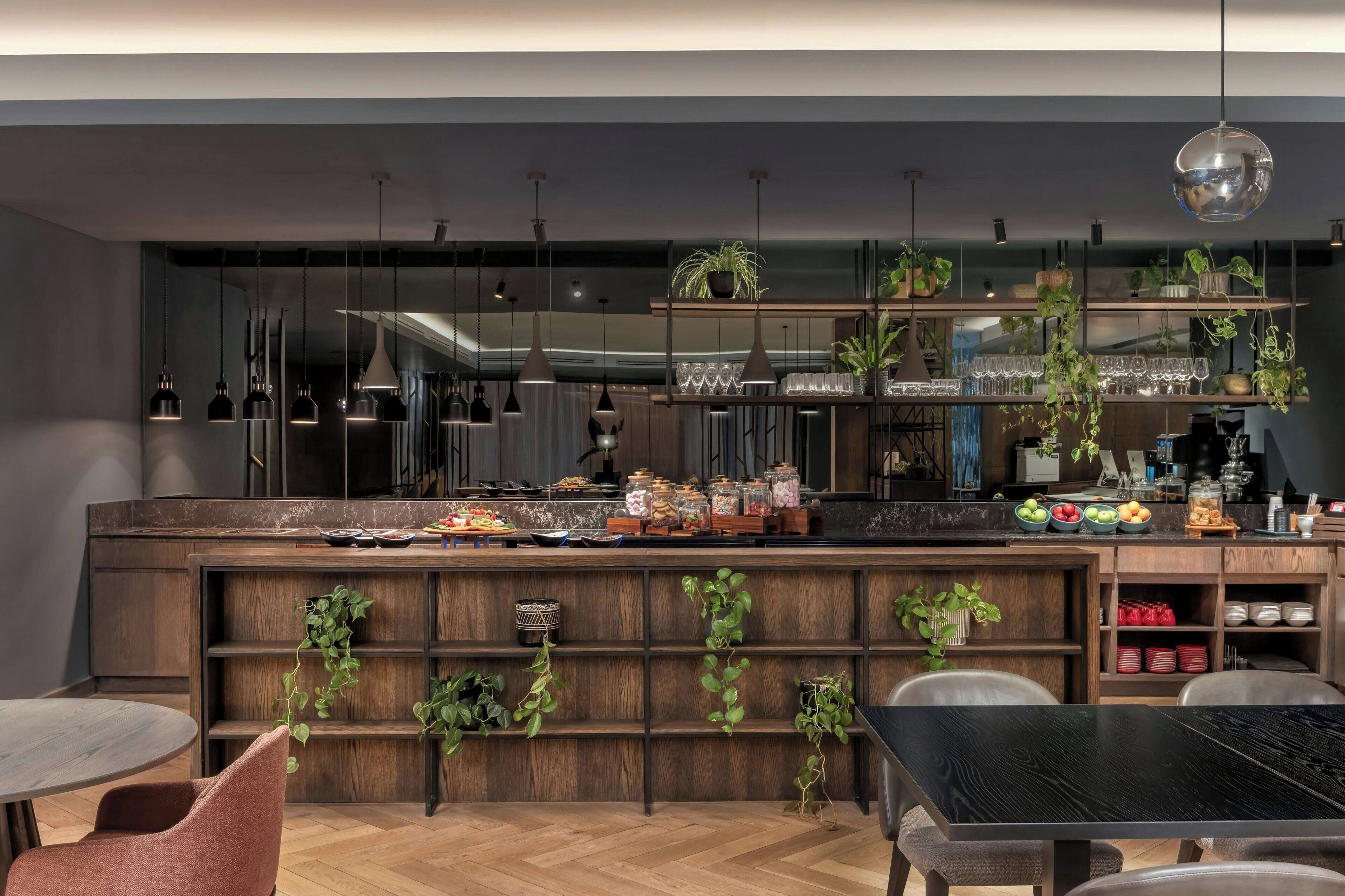 A modern kitchen with wooden shelves, hanging plants, and a variety of food items.