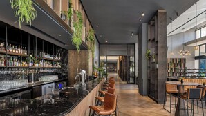A modern bar area with a long counter, leather bar stools, and a variety of bottles and glasses. - Johannesburg Marriott Hotel Melrose Arch (Johannesburg)