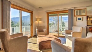 A spacious room with a large sliding glass door leading to a balcony with a mountain view. There are several plush armchairs and a sofa arranged around a central ottoman. - Hot Tub & Moat Mtn Views: North Conway Townhouse (North Conway)