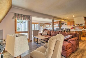 A cozy living room with a sofa, armchair, and a small table. There is a kitchen area with cabinets and a microwave. - Hot Tub & Moat Mtn Views: North Conway Townhouse (North Conway)