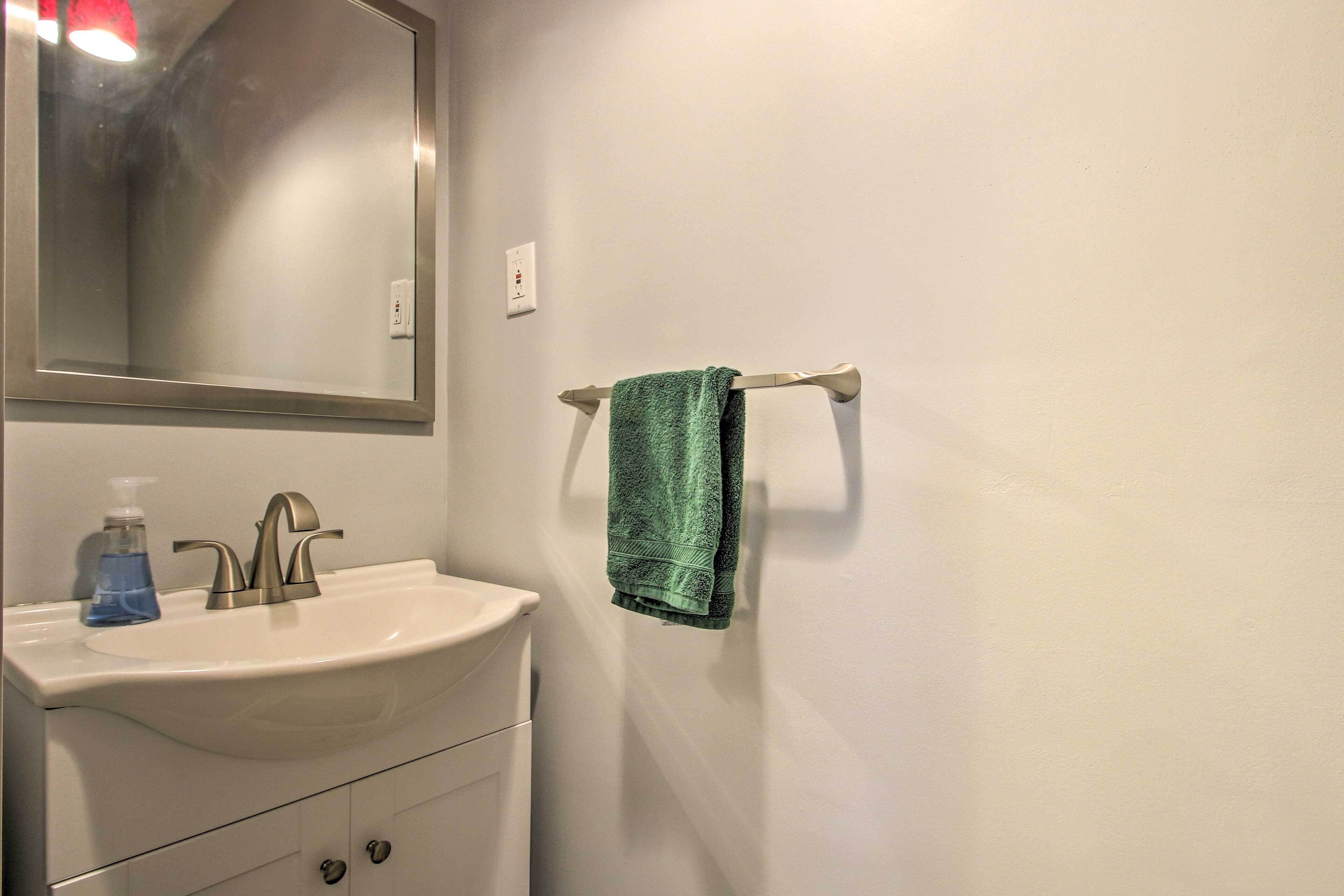 A bathroom with a white sink, a mirror, and a towel rack.
