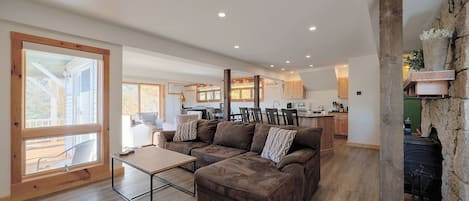 Un vaste espace de vie comprenant un canapé d’angle, une table basse et un coin repas avec des chaises et une table.