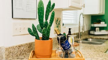 A kitchen counter with a potted cactus, a bottle of wine, and two glasses on a tray.