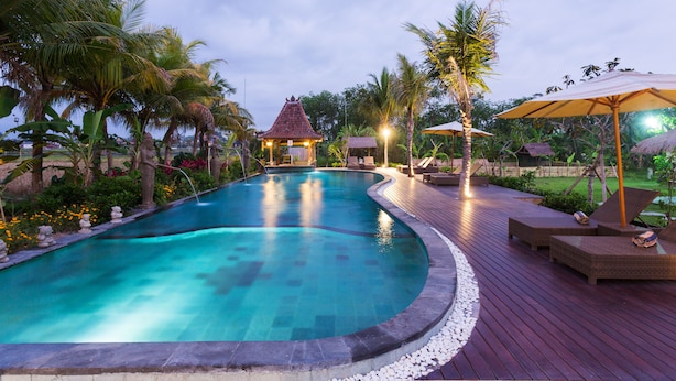 Une piscine avec une terrasse en bois, des chaises longues et des parasols.