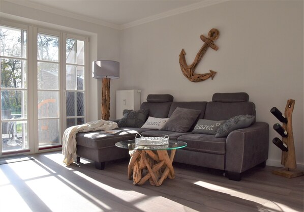 A living room with a grey sofa, a glass coffee table, and a wooden side table.