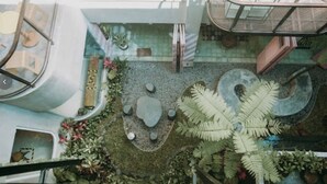 Un jardin intérieur à plusieurs niveaux, avec différentes espèces de plantes et un espace de repos central.