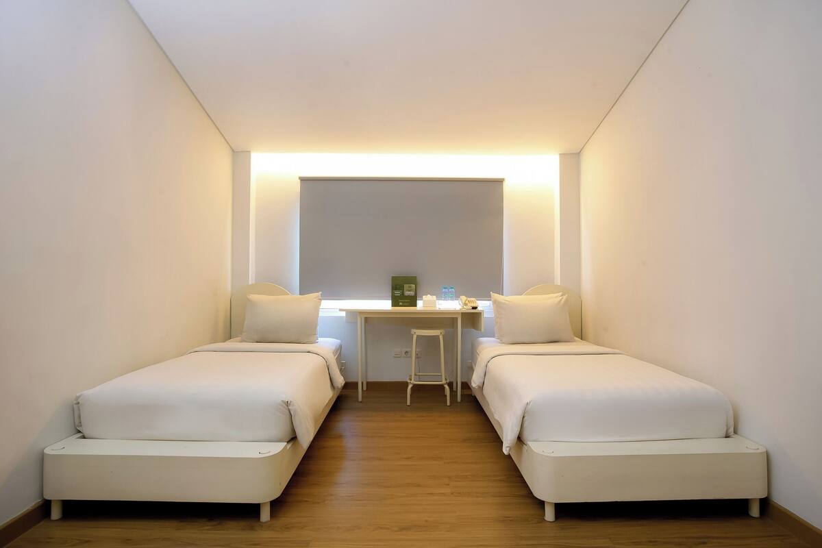 A room with two single beds, a small desk, and a chair.