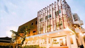 Un hôtel à plusieurs étages, doté d’un design moderne, avec une entrée imposante, des marches et un espace abrité.