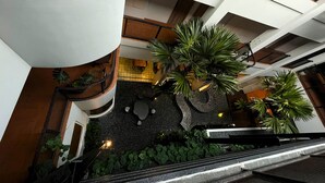 Un atrium à plusieurs niveaux, doté d’un jardin central, d’un escalier et d’un espace d’accueil.