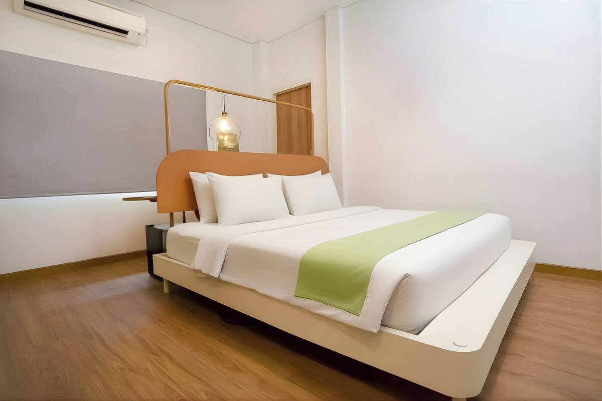 A modern bed with a wooden headboard, a bedside table, and a hanging light fixture.