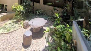 Un espace extérieur à plusieurs niveaux, agrémenté de structures en béton, de bancs en pierre et de diverses plantes.